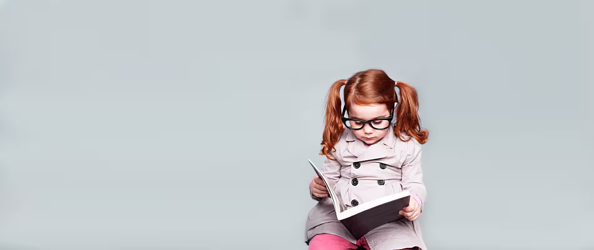 Kind mit Brille liest konzentriert in einem Buch – Symbolbild für Bildung, Förderung und kindliche Entwicklung